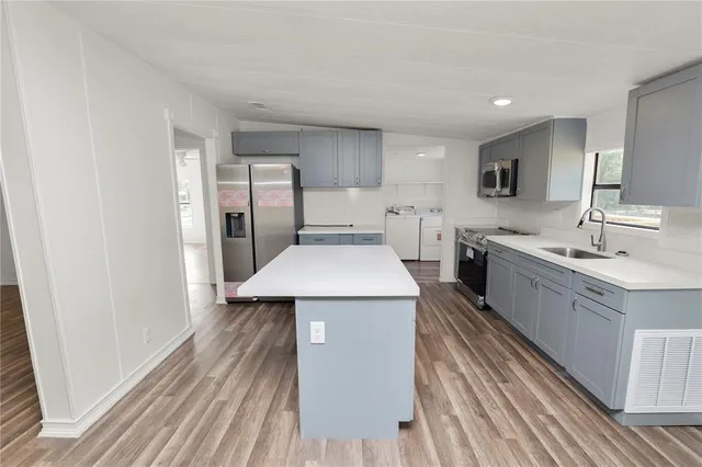 a kitchen with a sink and wooden floor