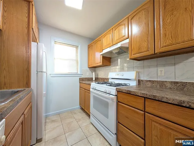 a kitchen with granite countertop cabinets stainless steel appliances a sink and a window