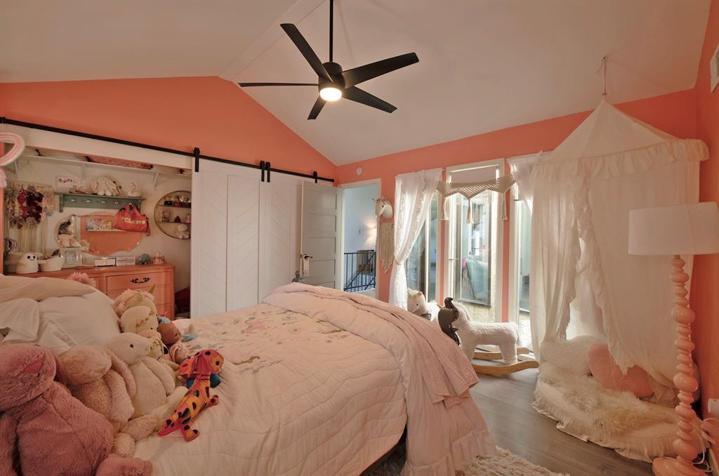 3915 Roma Court Rockwall, TX 75087 - Photo 27 of 40 Bedroom with a barn door, wood finished floors, ceiling fan, and high vaulted ceiling