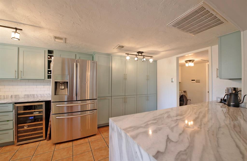 3915 Roma Court Rockwall, TX 75087 - Photo 4 of 40 Kitchen featuring stainless steel fridge, light stone counters, light tile patterned floors, beverage cooler, and a textured ceiling