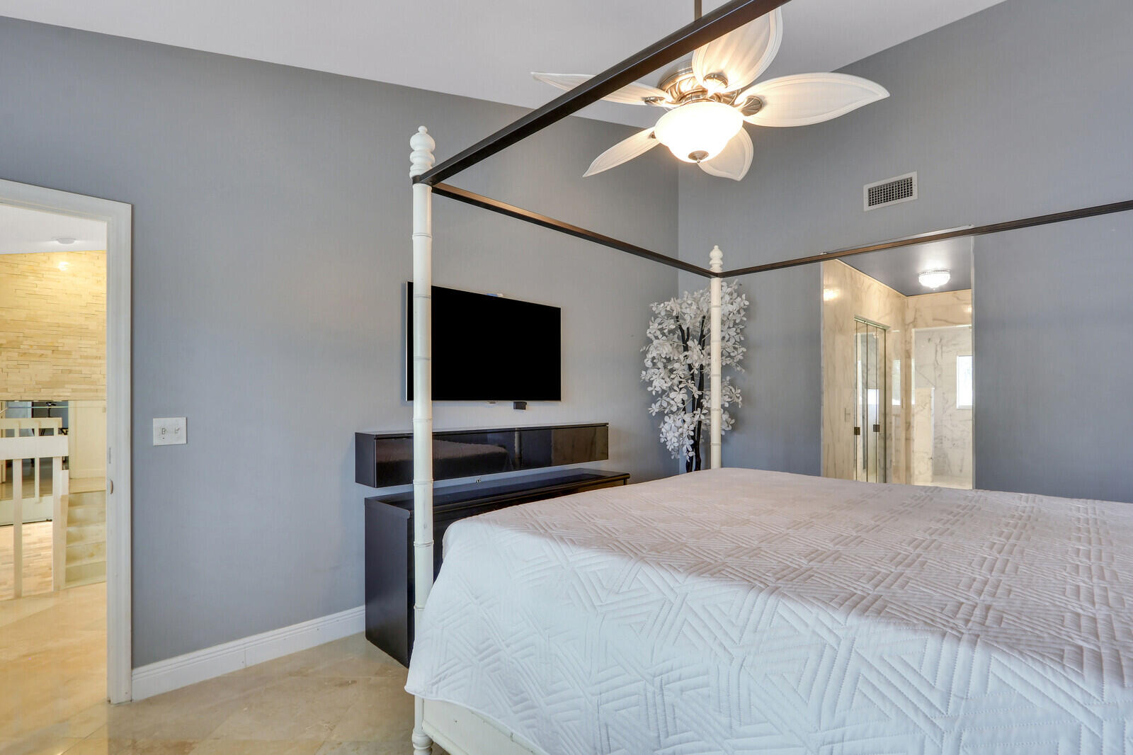 6136 Southeast Georgetown Place Hobe Sound, FL 33455 - Photo 28 of 46 a bedroom with a bed and a flat tv screen on dresser