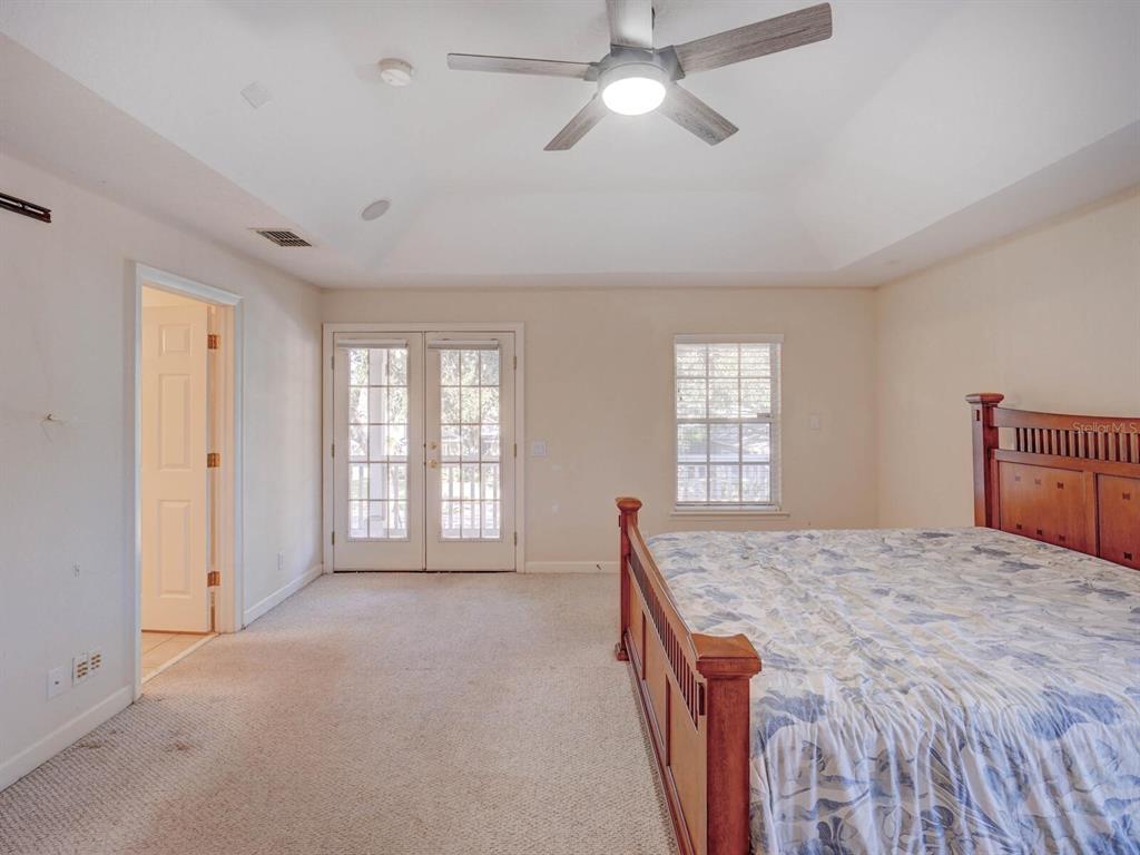 2217 Rising Creek Court Dunedin, FL 34698 - Photo 22 of 45 a spacious bedroom with a large bed and a chandelier