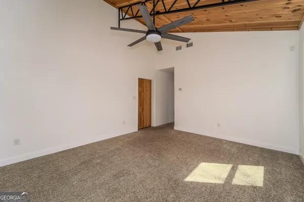 an empty room with a ceiling fan and carpet