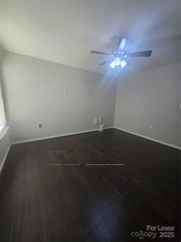 a view of room with hardwood floor and a ceiling fan