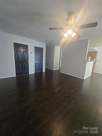 a view of an empty room with wooden floor and window