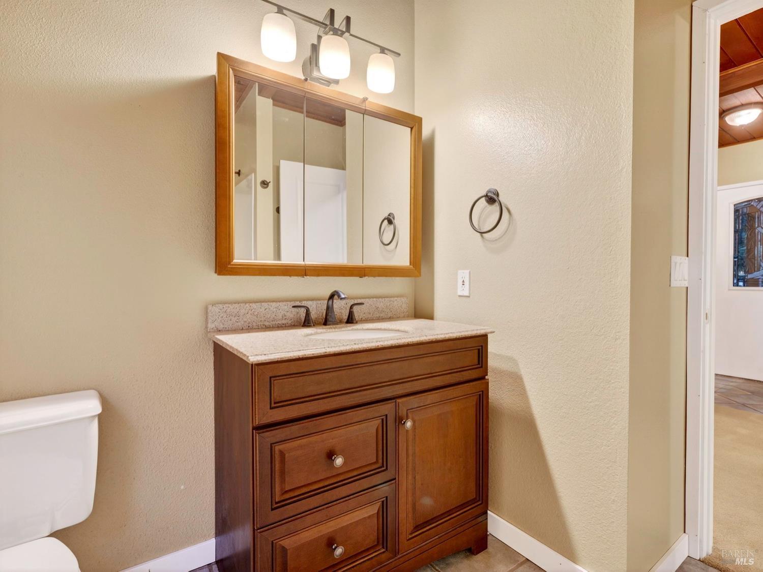 1290 Adobe Canyon Road Kenwood, CA 95452 - Photo 21 of 62 a bathroom with a toilet a sink a mirror and a window
