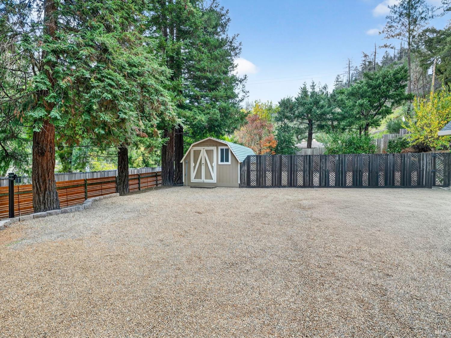 1290 Adobe Canyon Road Kenwood, CA 95452 - Photo 8 of 62 a view of a backyard with large trees and wooden fence