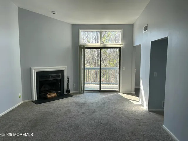 an empty room with windows and fireplace