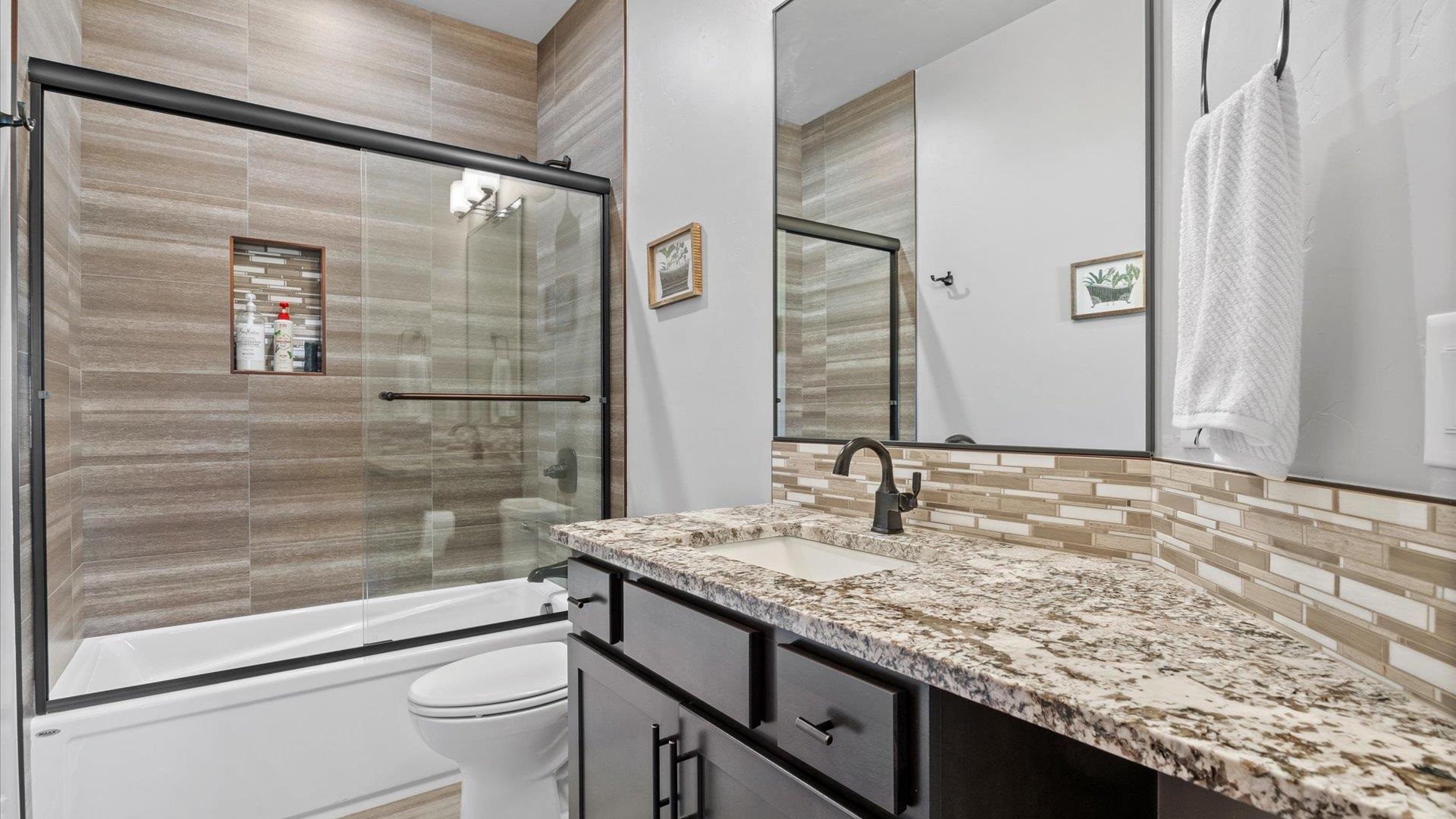 379 High Desert Road Grand Junction, CO 81507 - Photo 31 of 42 a bathroom with a granite countertop sink a toilet a mirror and shower