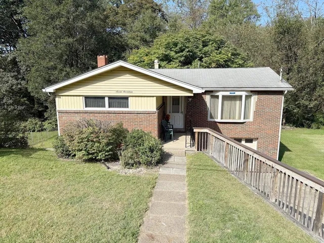 a view of a house with brick walls and a yard with plants