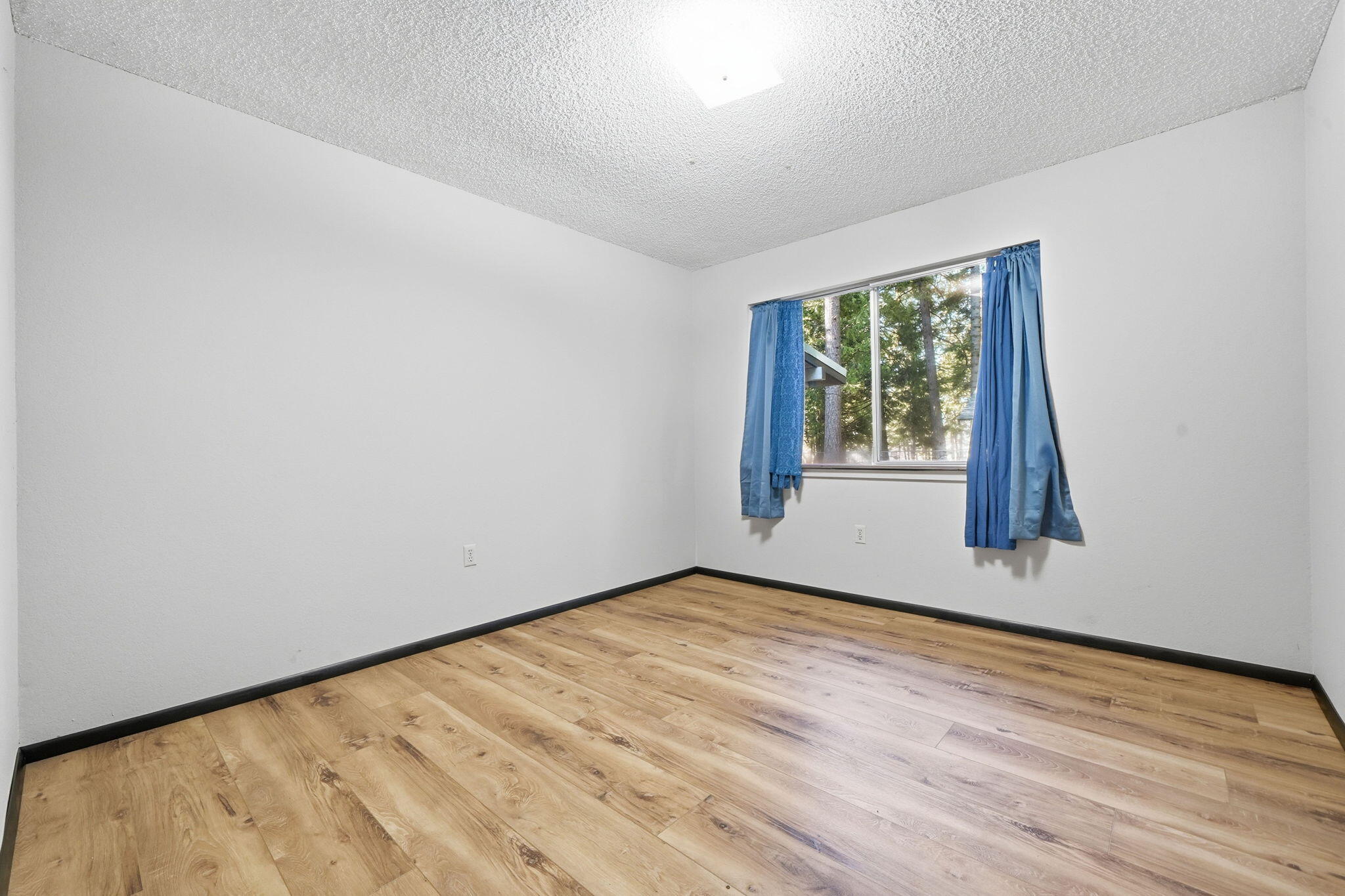 8489 Starlite Pines Road Shingletown, CA 96088 - Photo 13 of 26 wooden floor in an empty room with a window