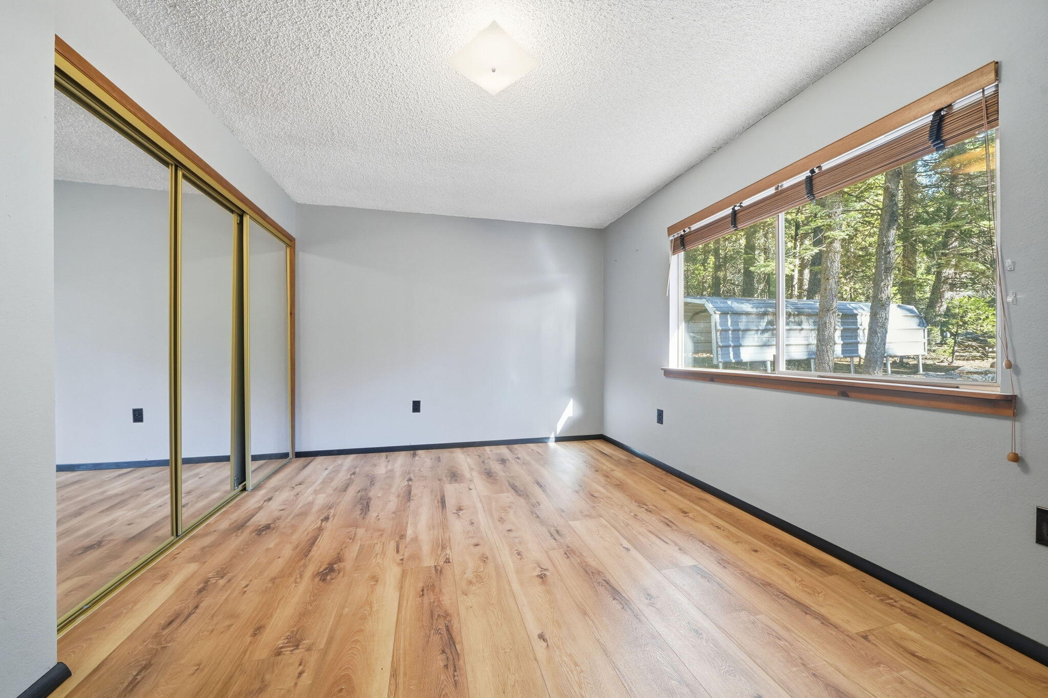 8489 Starlite Pines Road Shingletown, CA 96088 - Photo 10 of 26 a view of an empty room with wooden floor and a window