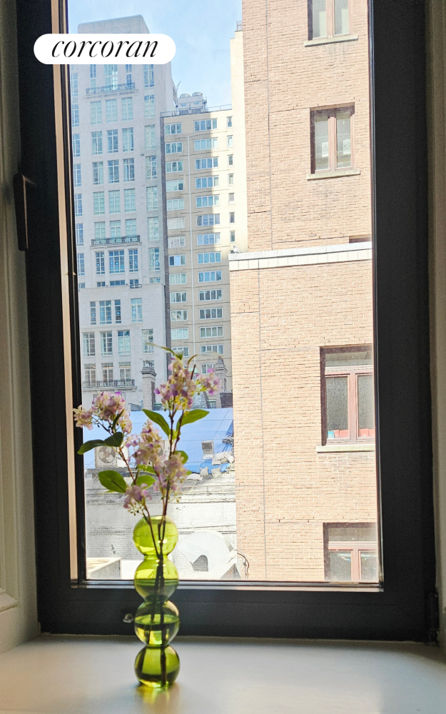 205 West 57th Street, Unit 3DC Manhattan, NY 10019 - Photo 9 of 18 a vase of flowers sitting next to a window