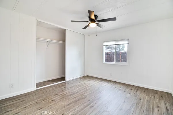 an empty room with wooden floor fan and windows