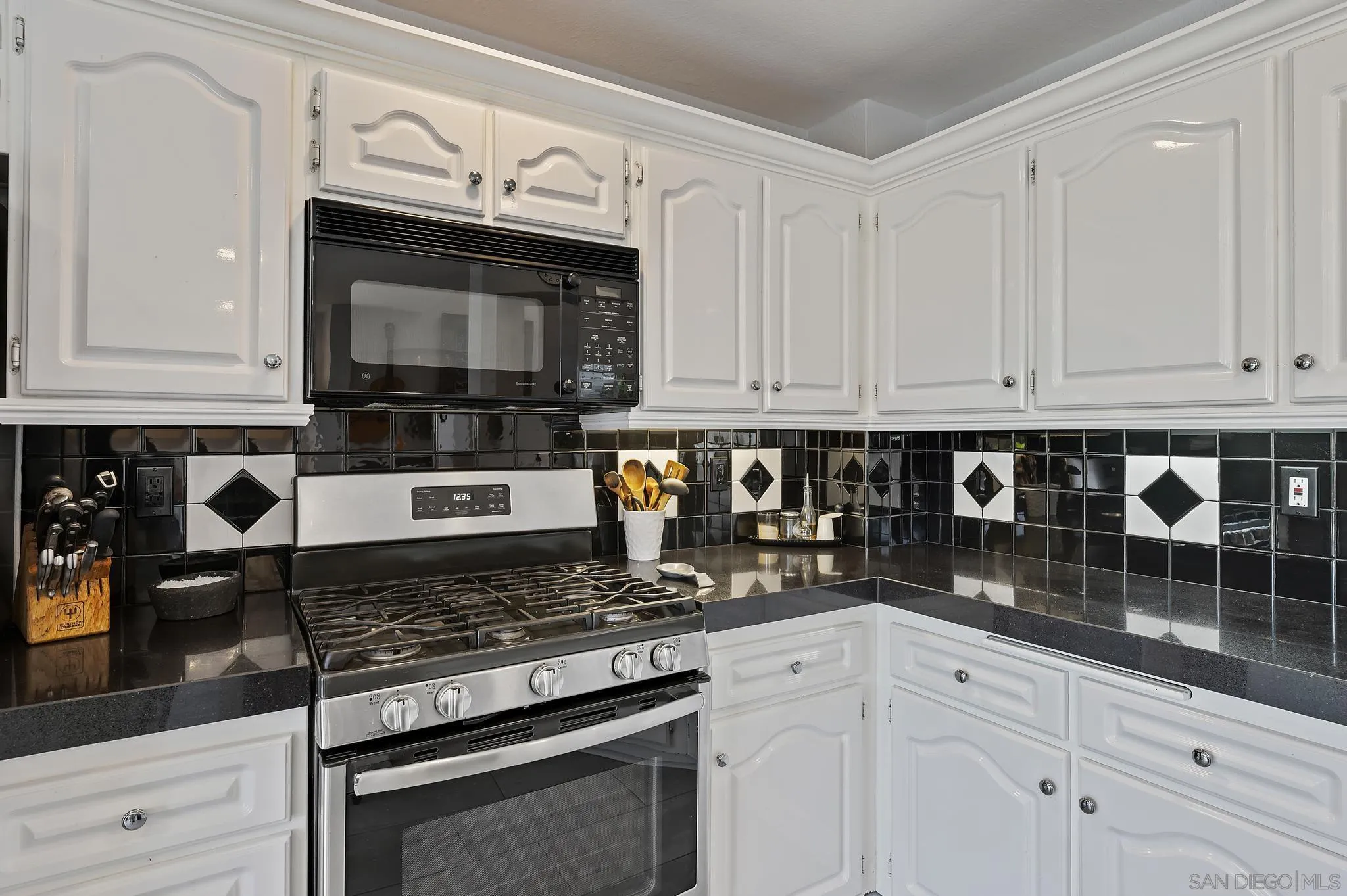 7015 Lavender Way Carlsbad, CA 92011 - Photo 13 of 67 a kitchen with granite countertop white cabinets and stainless steel appliances