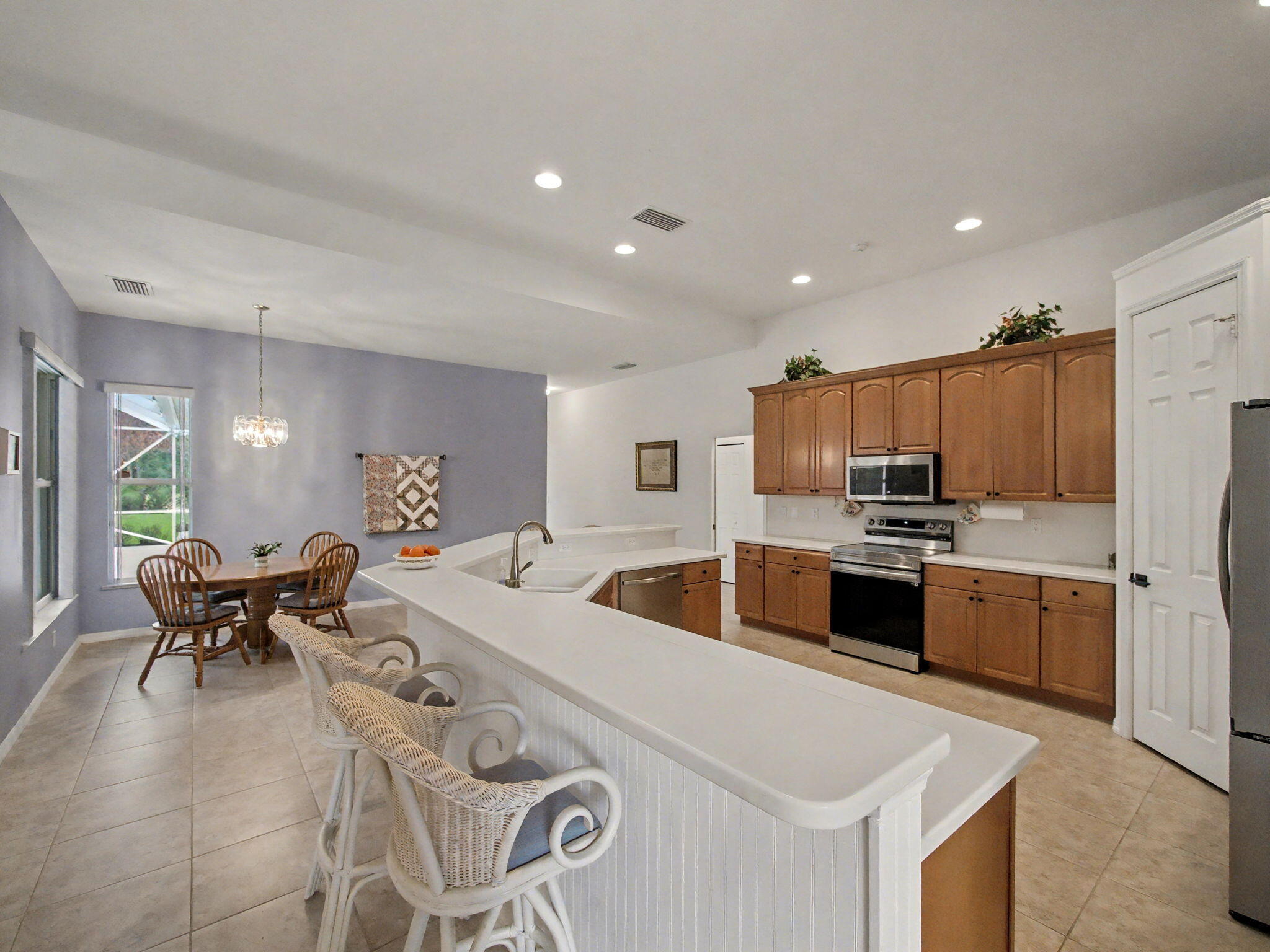 8122 Southwest Yachtsmans Drive Stuart, FL 34997 - Photo 13 of 43 a large white kitchen with a refrigerator a stove a sink a dining table and chairs