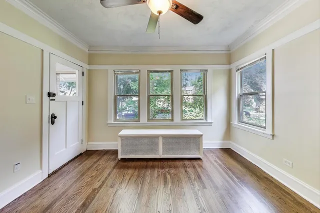 an empty room with wooden floor chandelier fan and windows
