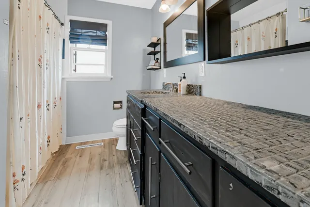 a kitchen with granite countertop a sink cabinets and wooden floor
