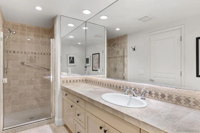 a bathroom with a granite countertop sink mirror and shower