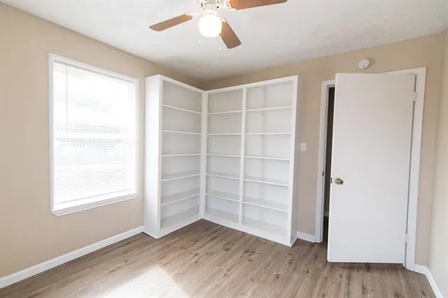 a view of an empty room with a window and wooden floor
