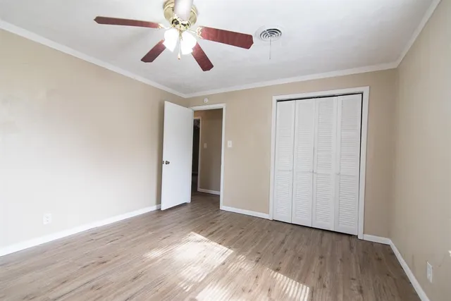 an empty room with wooden floor chandelier fan and closet in a room
