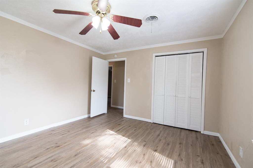 2501 Park Street Commerce, TX 75428 - Photo 13 of 24 an empty room with wooden floor chandelier fan and closet in a room