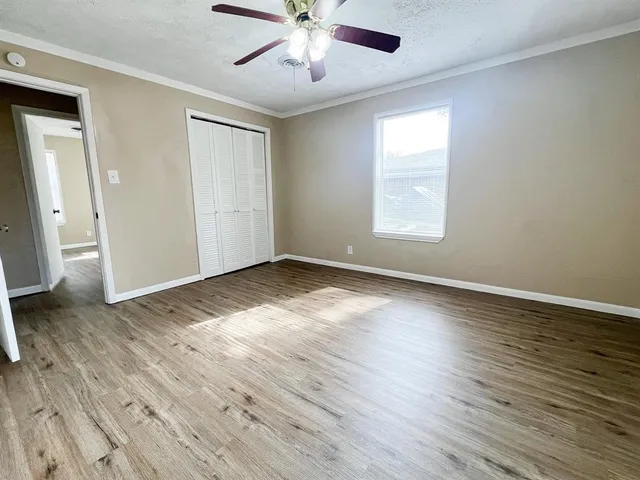 an empty room with wooden floor chandelier fan and windows