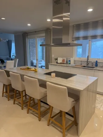 a kitchen with stainless steel appliances granite countertop a table chairs sink and white cabinets