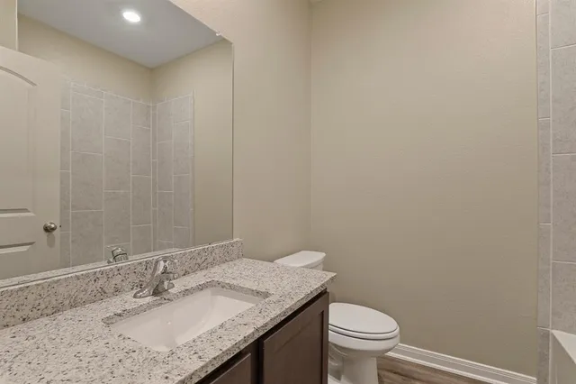 a bathroom with a granite countertop sink a toilet and a mirror