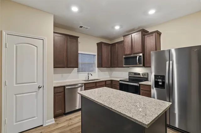 a kitchen with a refrigerator a sink a stove and cabinets