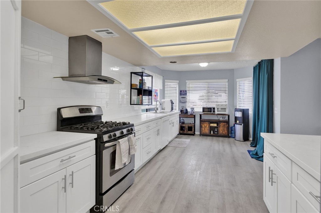 9224 Beekley Road Phelan, CA 92371 - Photo 10 of 52 a kitchen with stainless steel appliances granite countertop a stove top oven a sink dishwasher and a refrigerator with wooden floor