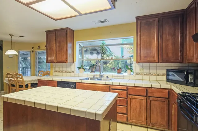 a kitchen with stainless steel appliances granite countertop wooden cabinets a sink and a large window