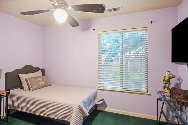 a bedroom with a bed a flat screen tv and a window