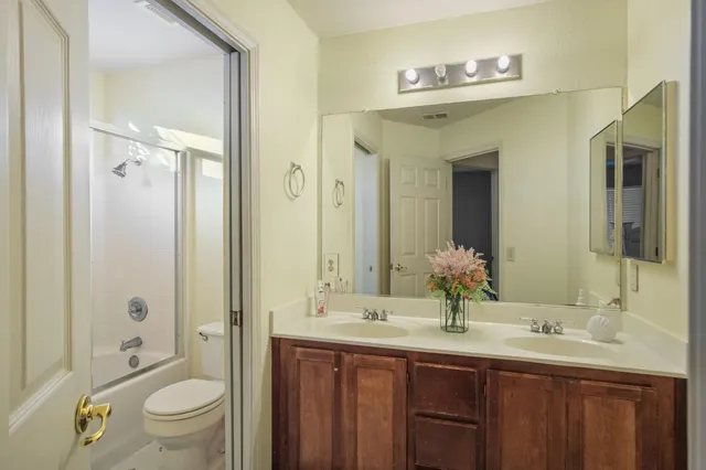 a bathroom with a granite countertop sink a toilet and a large mirror