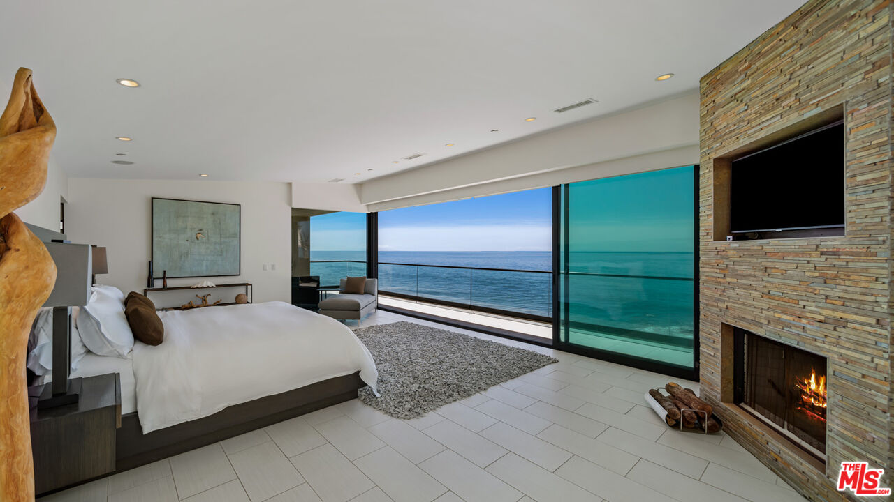 25250 Malibu Road Malibu, CA 90265 - Photo 33 of 66 a bedroom with a bed a fireplace and television