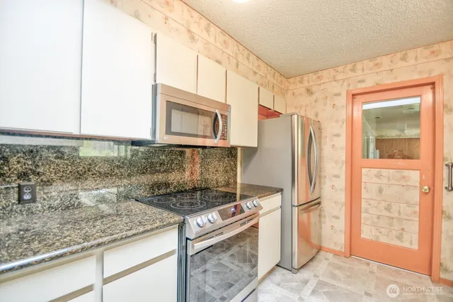 a kitchen with stainless steel appliances granite countertop a refrigerator and a stove