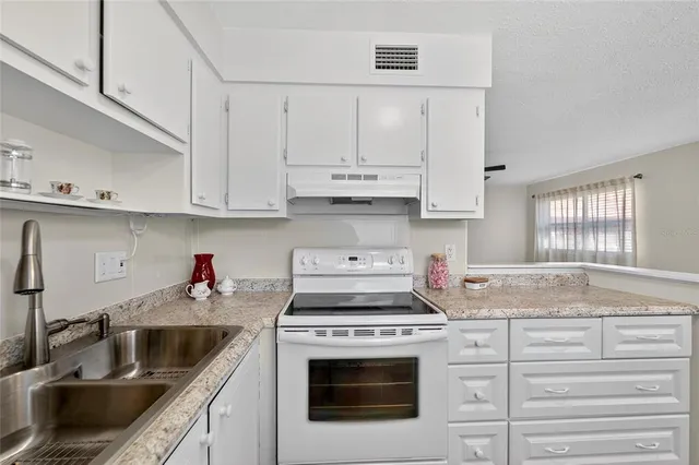 a kitchen with granite countertop white cabinets and a sink