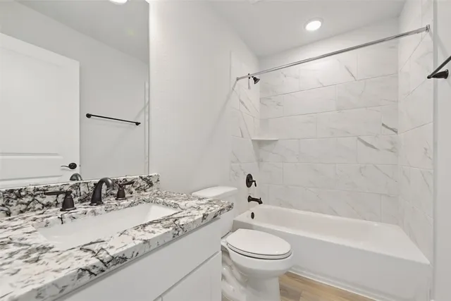 a bathroom with a granite countertop sink a toilet and bathtub