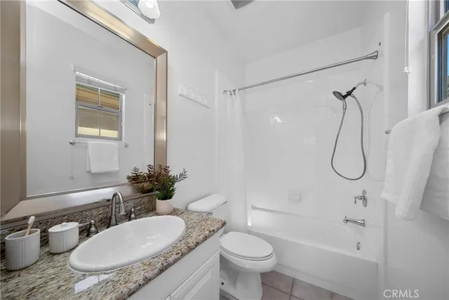 a bathroom with a granite countertop sink toilet a mirror and shower