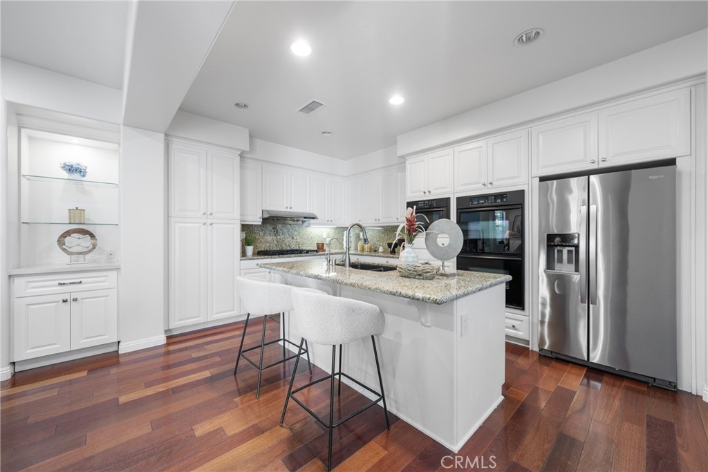 26 Twin Gables Irvine, CA 92620 - Photo 9 of 36 a kitchen with a refrigerator a sink dishwasher and a stove with wooden floor