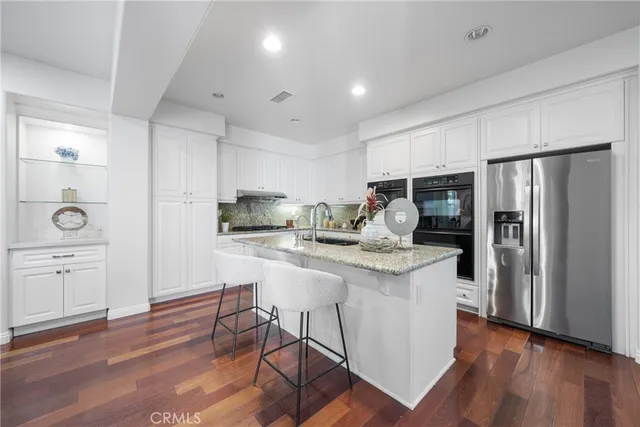 a kitchen with a refrigerator a sink dishwasher and a stove with wooden floor