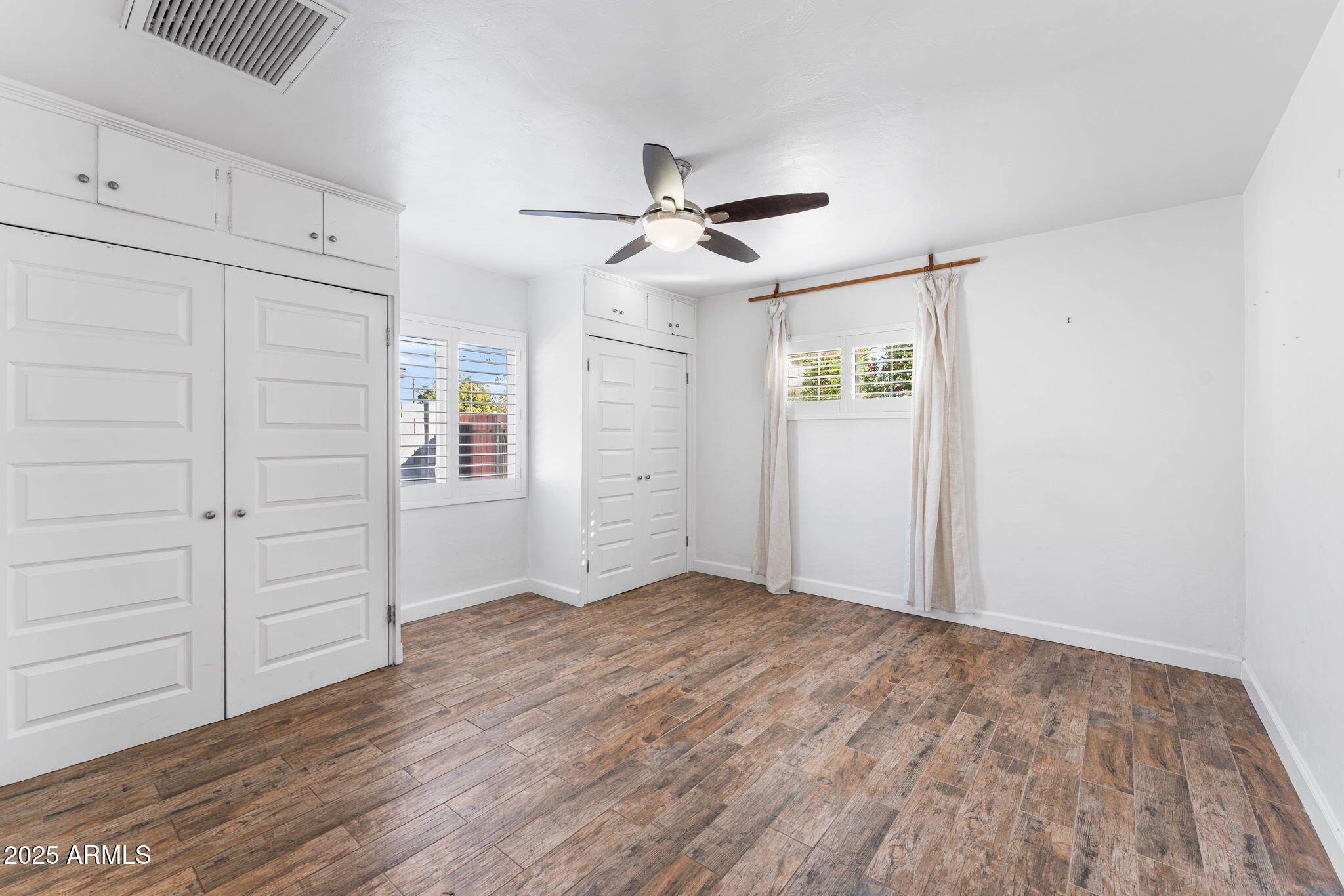 1334 West Sells Drive Phoenix, AZ 85013 - Photo 22 of 32 an empty room with wooden floor ceiling fan and windows