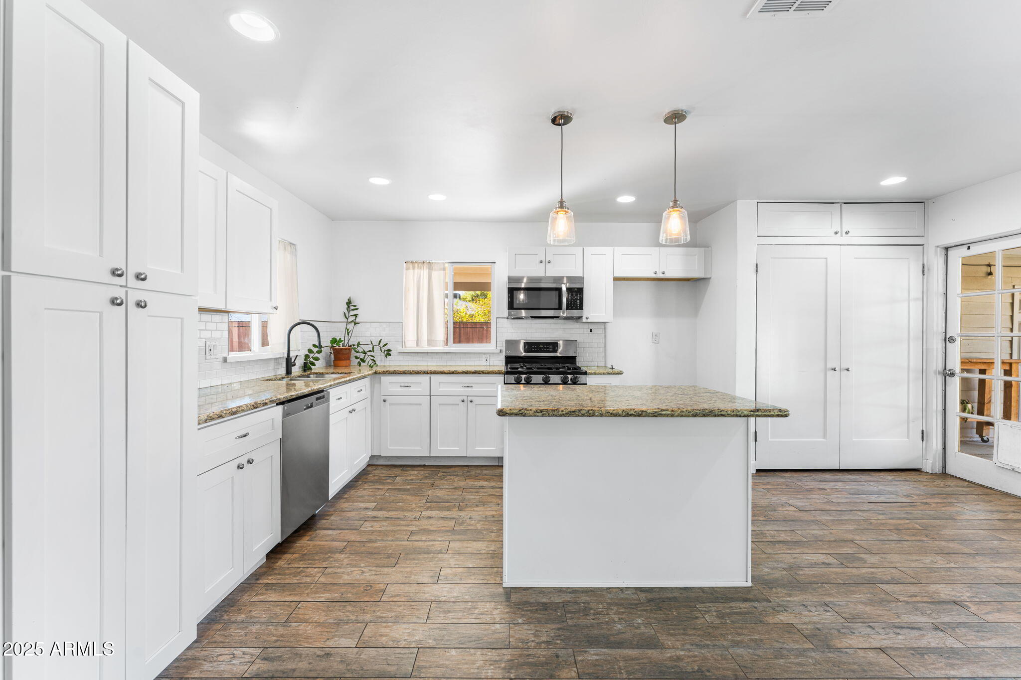 1334 West Sells Drive Phoenix, AZ 85013 - Photo 9 of 32 a kitchen with stainless steel appliances granite countertop a stove top oven a refrigerator a sink and white cabinets with wooden floor