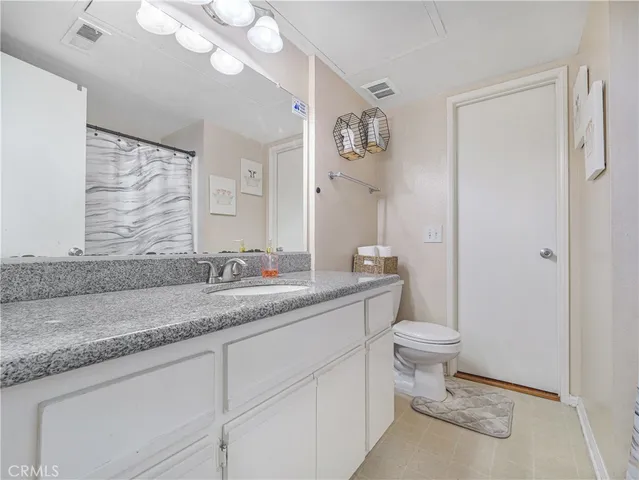 a bathroom with a granite countertop sink a toilet and a mirror