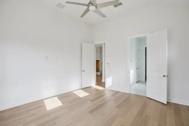 an empty room with wooden floor and ceiling fan