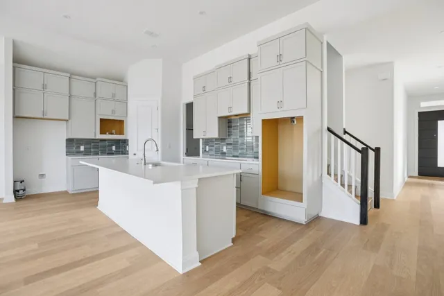 a large white open kitchen with cabinets and wooden floor