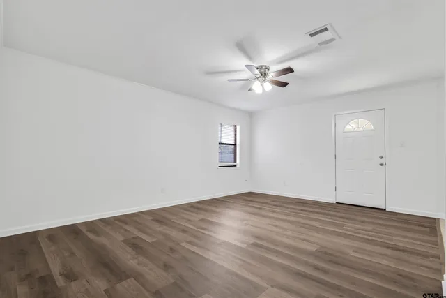 an empty room with wooden floor and fan