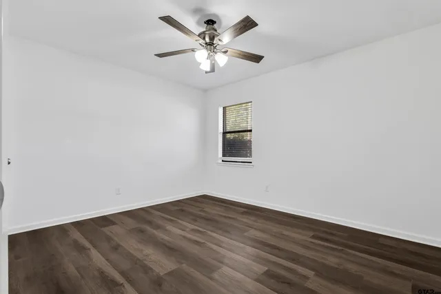 an empty room with wooden floor and ceiling fan