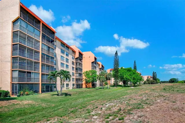 a front view of multi story residential apartment building with a yard and plants