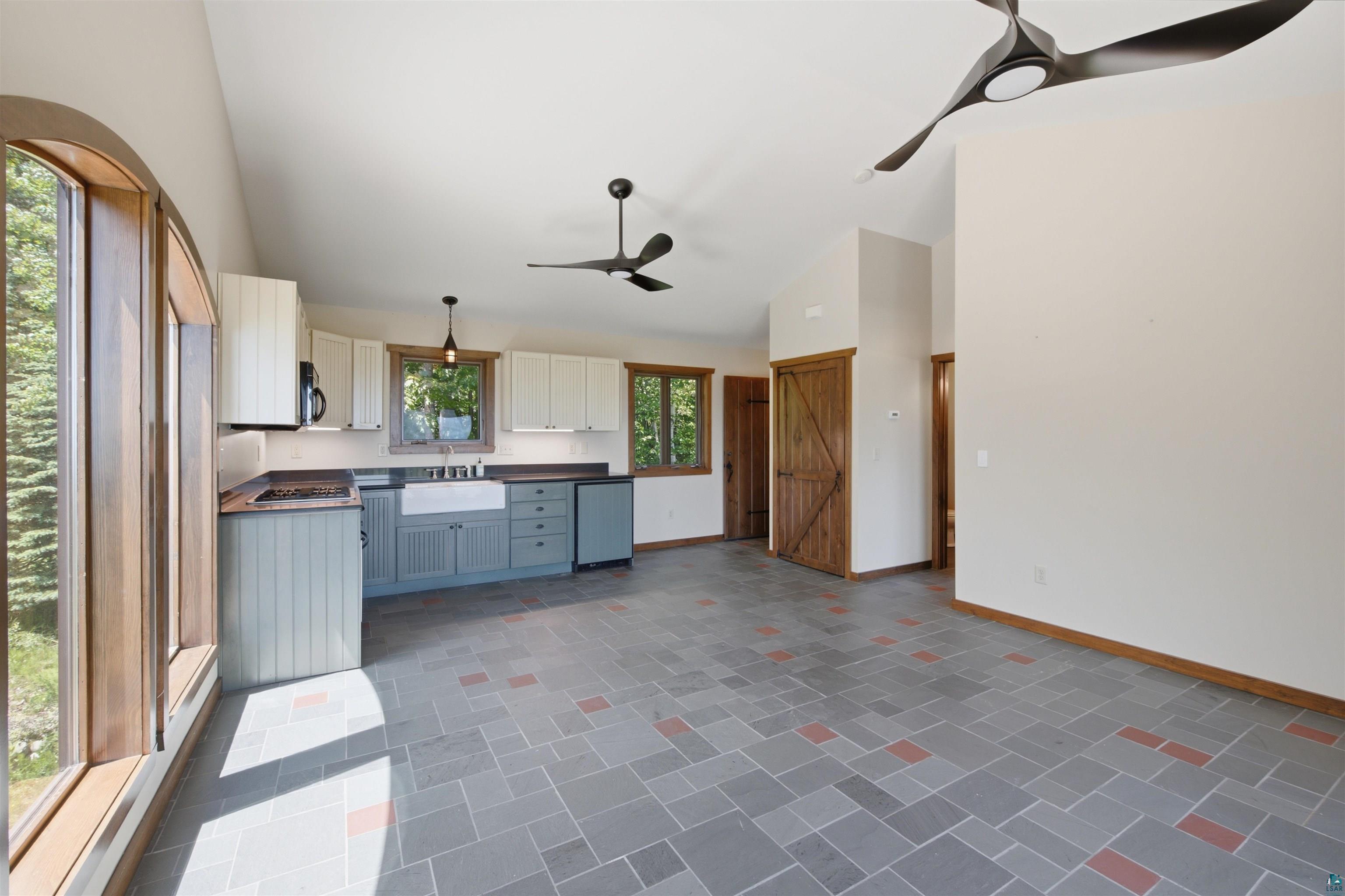 86270 Meyers-Olson Road Bayfield, WI 54814 - Photo 13 of 33 Vaulted ceiling kitchen featuring a farmhouse sink, two-tone cabinetry, and an arched window